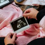 Woman holding sonogram over pink blanket