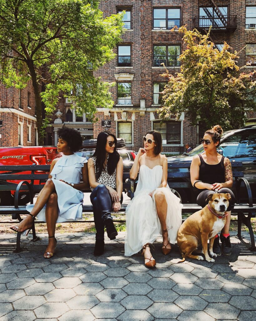 women sitting outside with dog on a bench.