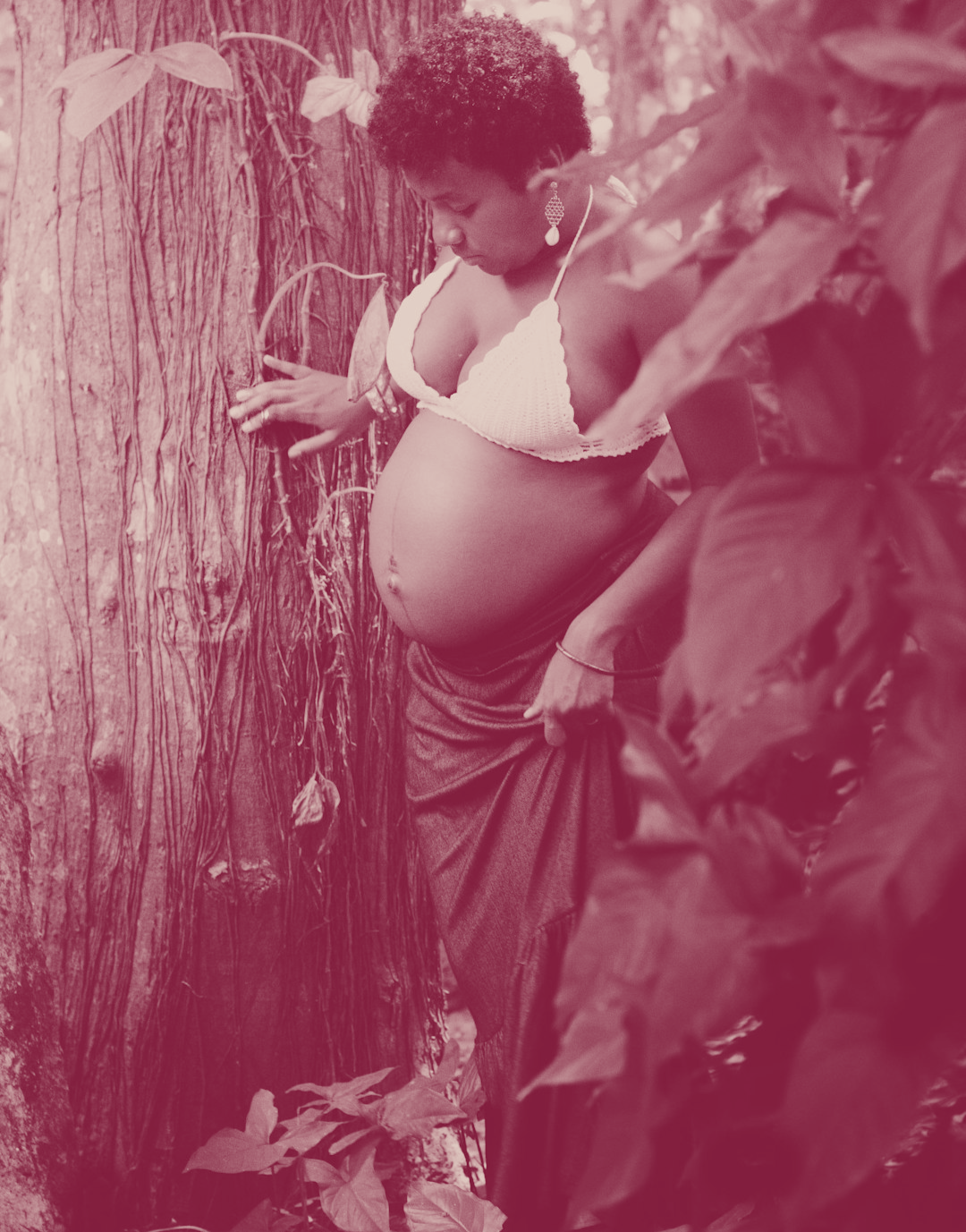 Pregnant women standing net to a tree.