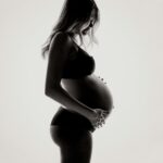 Pregnant woman holding belly with a white background.