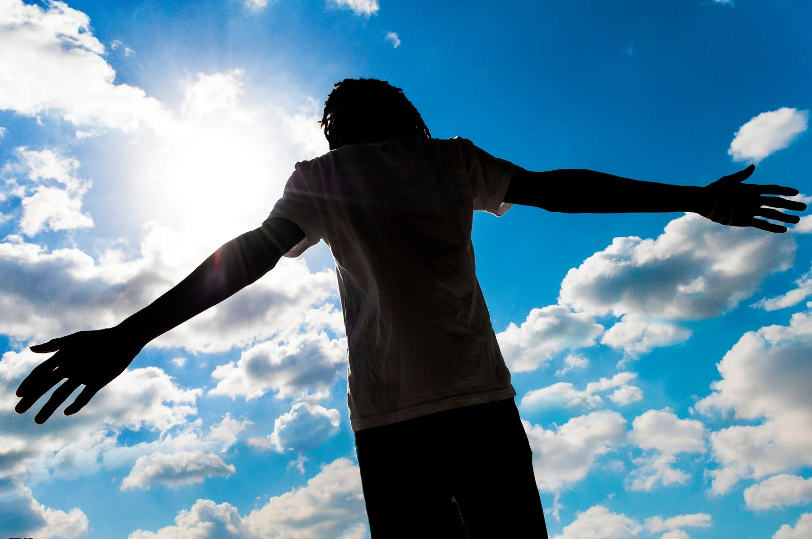 man with open arms and sky